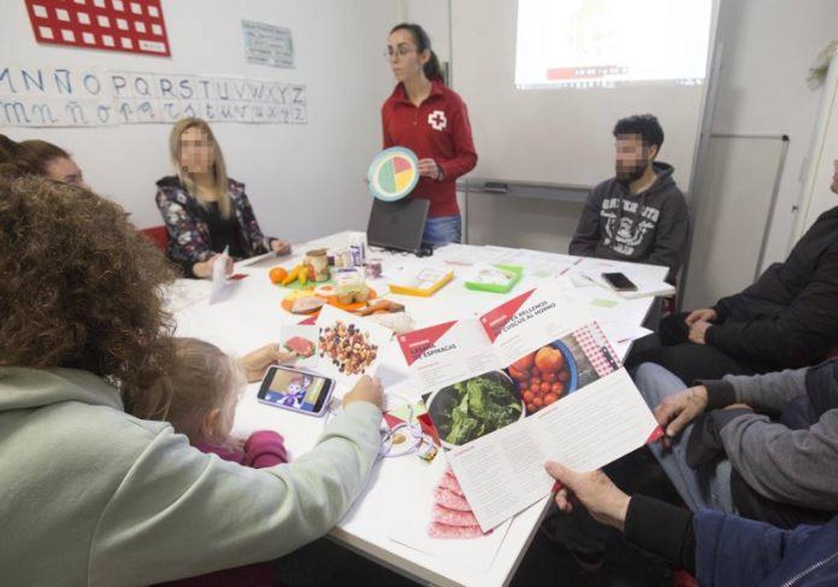 Clara González, técnica de Salud de Cruz Roja, enseña a personas vulnerables cómo ahorrar y seguir una dieta saludable en uno de los talleres de nutrición de la entidad en Valencia.