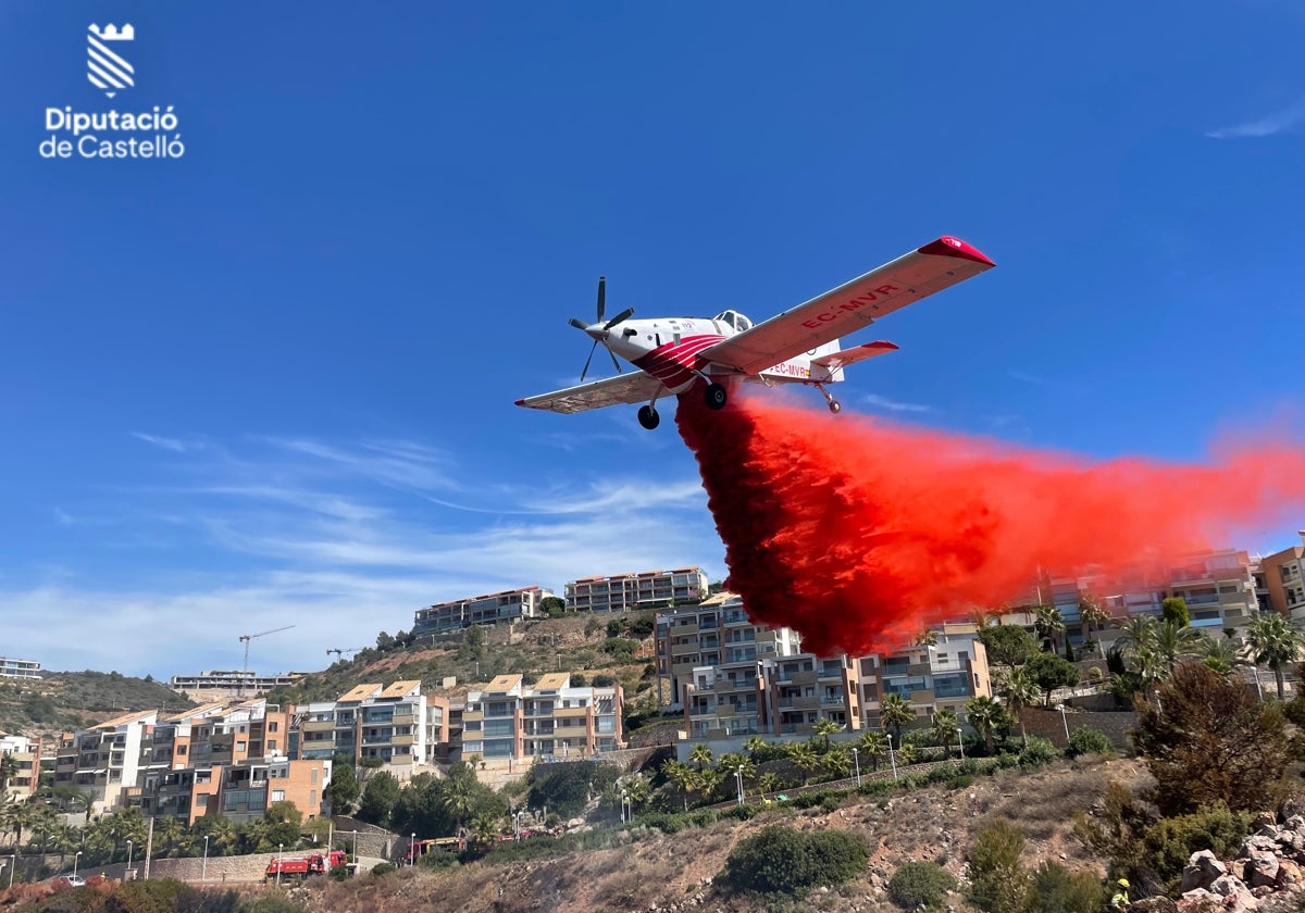 Una avioneta descarga agua con productos químicos retardantes en la zona del incendio.