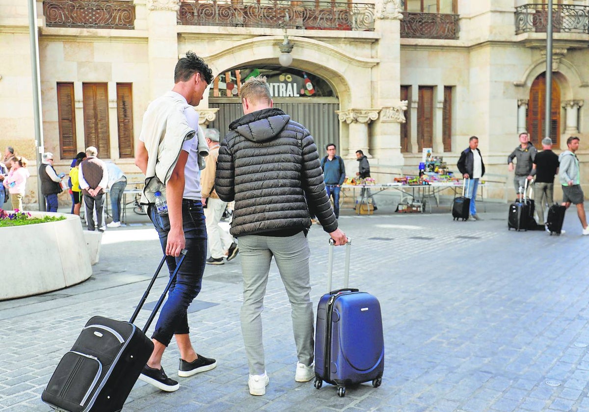 Jóvenes, con maleta en mano, recorren el centro de Valencia este lunes.