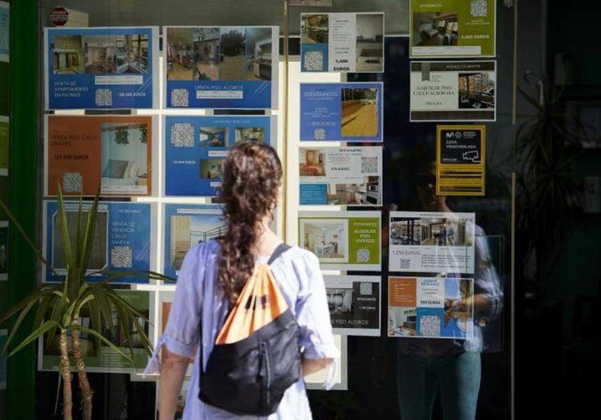 Una mujer contempla los precios de los pisos en una inmobiliaria.