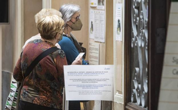 Tres personas en la entrada del Museo de Cerámica en el que anuncia en cartel el cierre de algunas salas en una imagen de archivo.