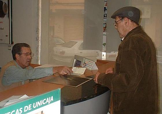 Pensionistas con una cartilla de ahorro en el banco, en una imagen de archivo.