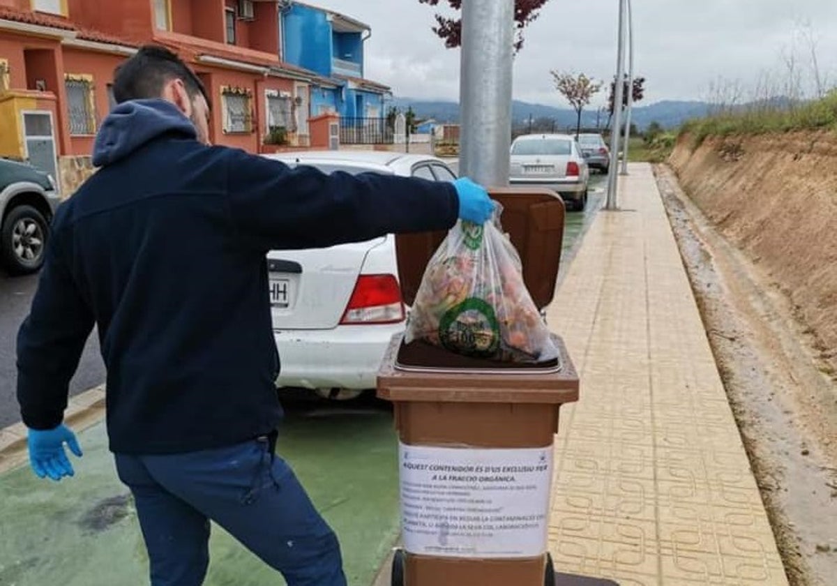 Un vecino deposita los restos de orgánica en el contenedor.