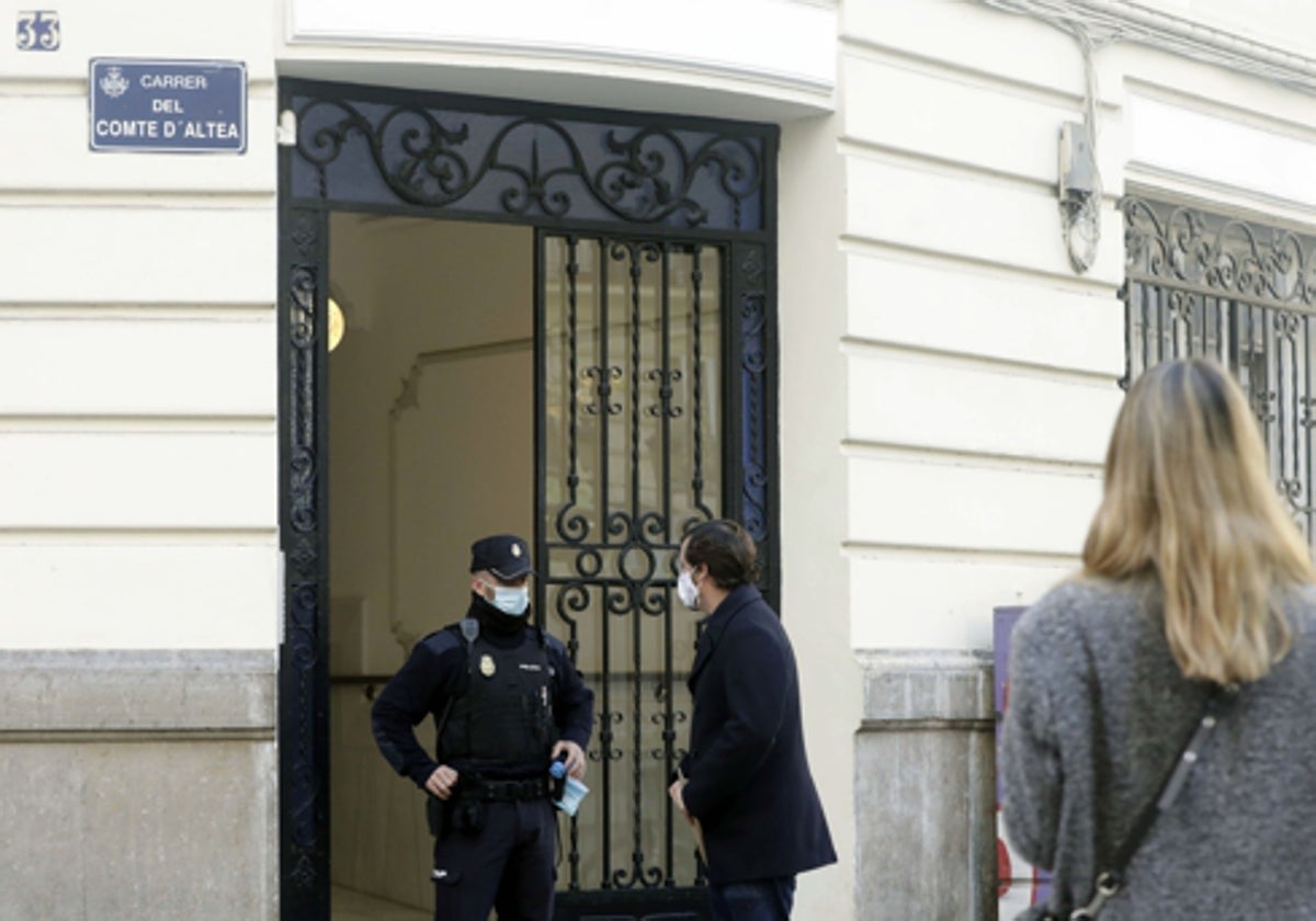 Un policía haba con un hombre en la puerta de la finca donde tuvo lugar el crimen.