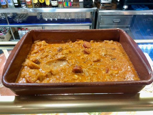 Imagen secundaria 2 - Morell junto a la pizarra de tapas; el bocadillo de figatells con cebolla caramelizada y la tapa de callos que guisan con almendras y guindillla. 