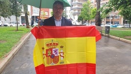 El edil Guillermo Barber con una bandera del país en la plaza de España de Gandia.