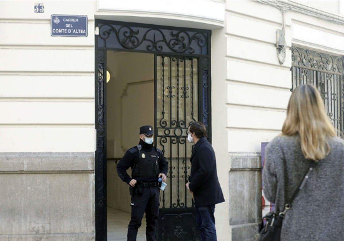 Un policía habla con un hombre en la puerta de la finca donde tuvo lugar el crimen.