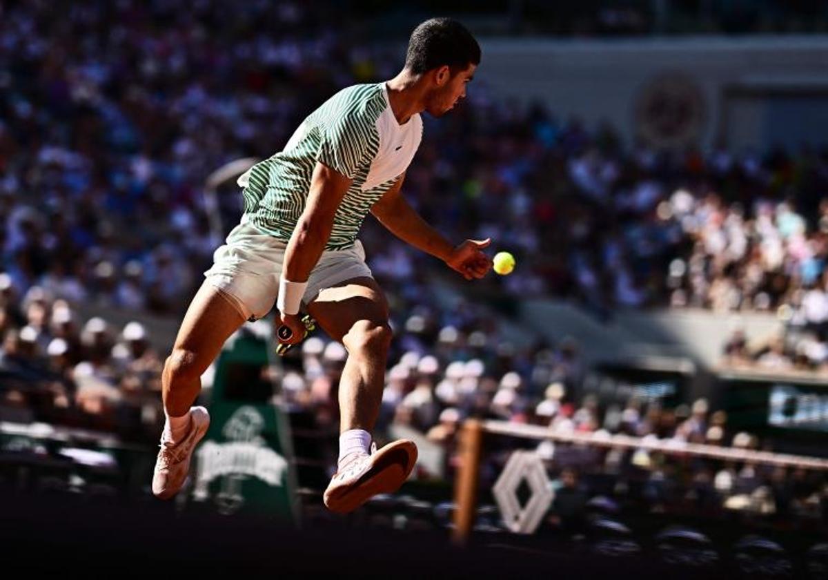 Carlos Alcaraz devuelve una pelota bajo piernas en Roland Garros.