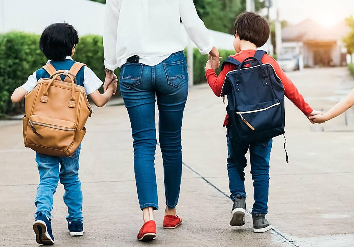 Una madre lleva a sus hijos al colegio.