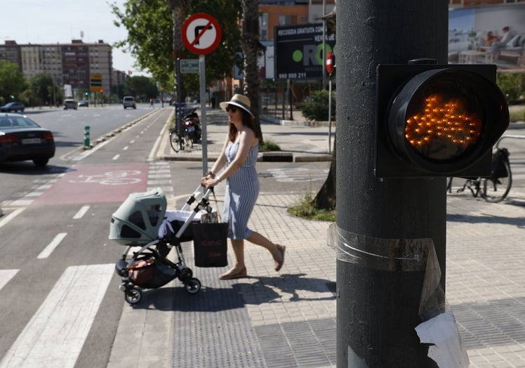 Una mujer atraviesa un cruce junto a un semáforo para ciclistas que no es reglamentario.