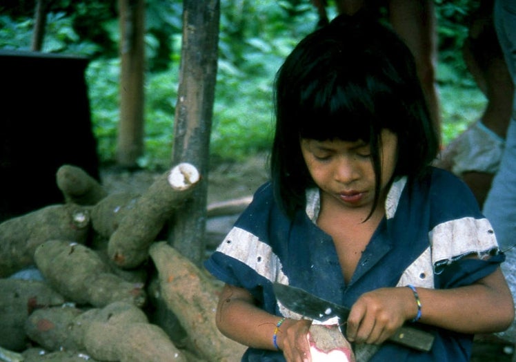 Una niña pelando yuca.