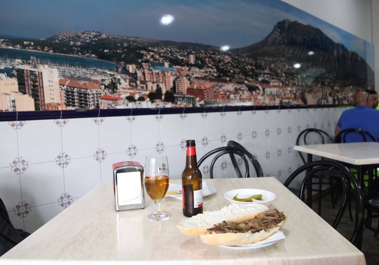 Una de las mesas preparadas para almorzar junto a una imagen panorámica de Dénia.