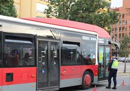 Un agente junto a un autobús de la EMT.