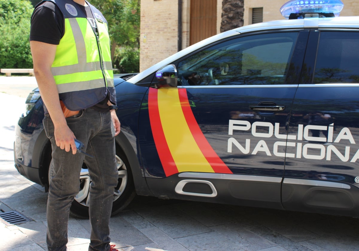 Imagen de archivo de un policía junto a un coche patrulla.