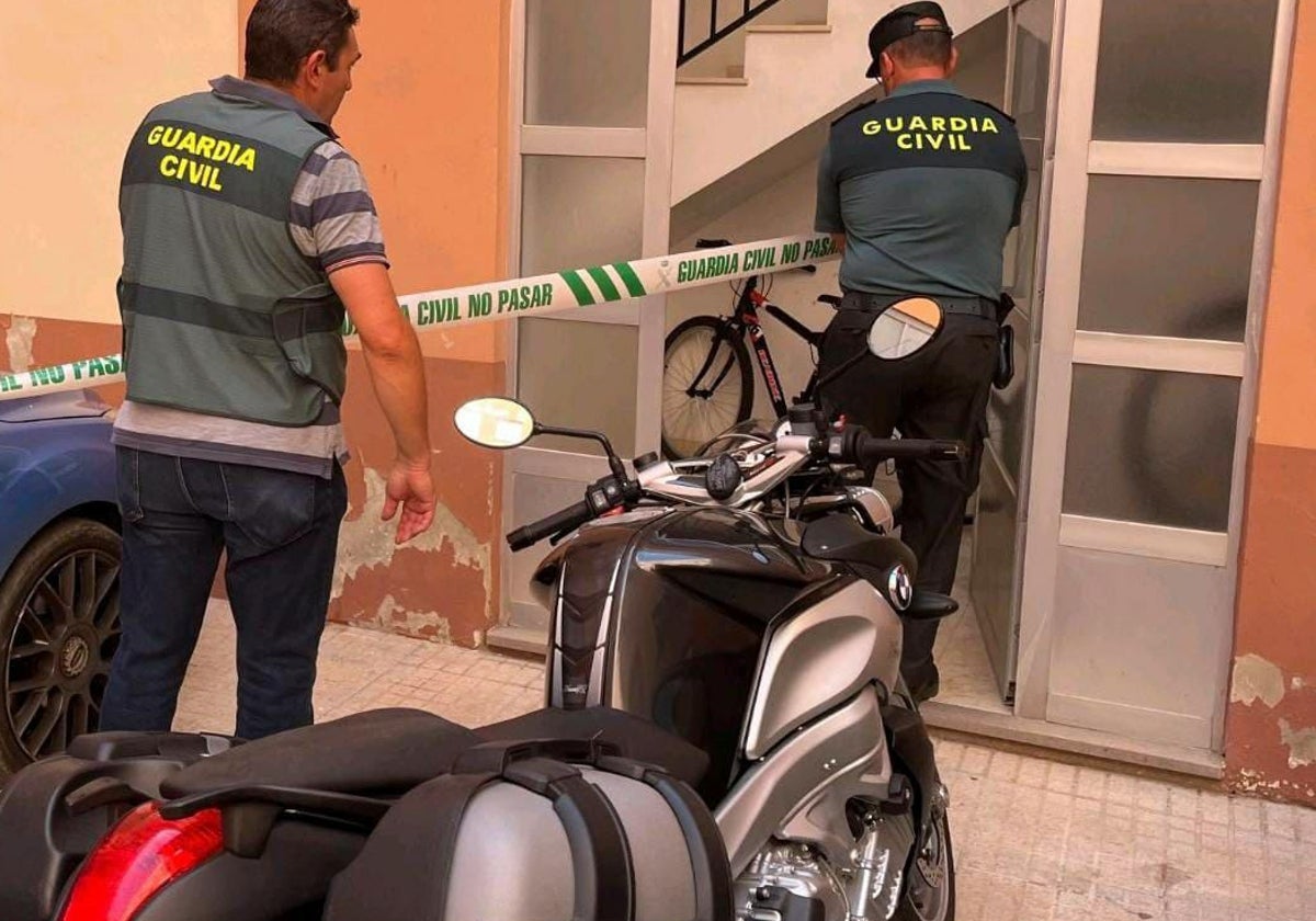 Dos agentes colocan un precinto en la puerta de la casa de la víctima.