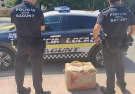 Dos policías locales de Sagunto junto a uno de los fardos de hachís.