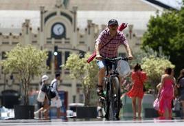 Un hombre va en bicicleta por el centro de Valencia.