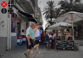 Una pareja de peatones cruza por delante de uno de los bares con terraza en la calle Eugenia Viñes.