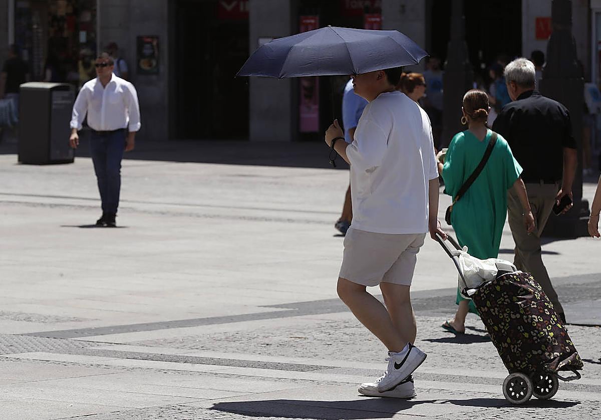 Un hombre se protege del sol con un paraguas.