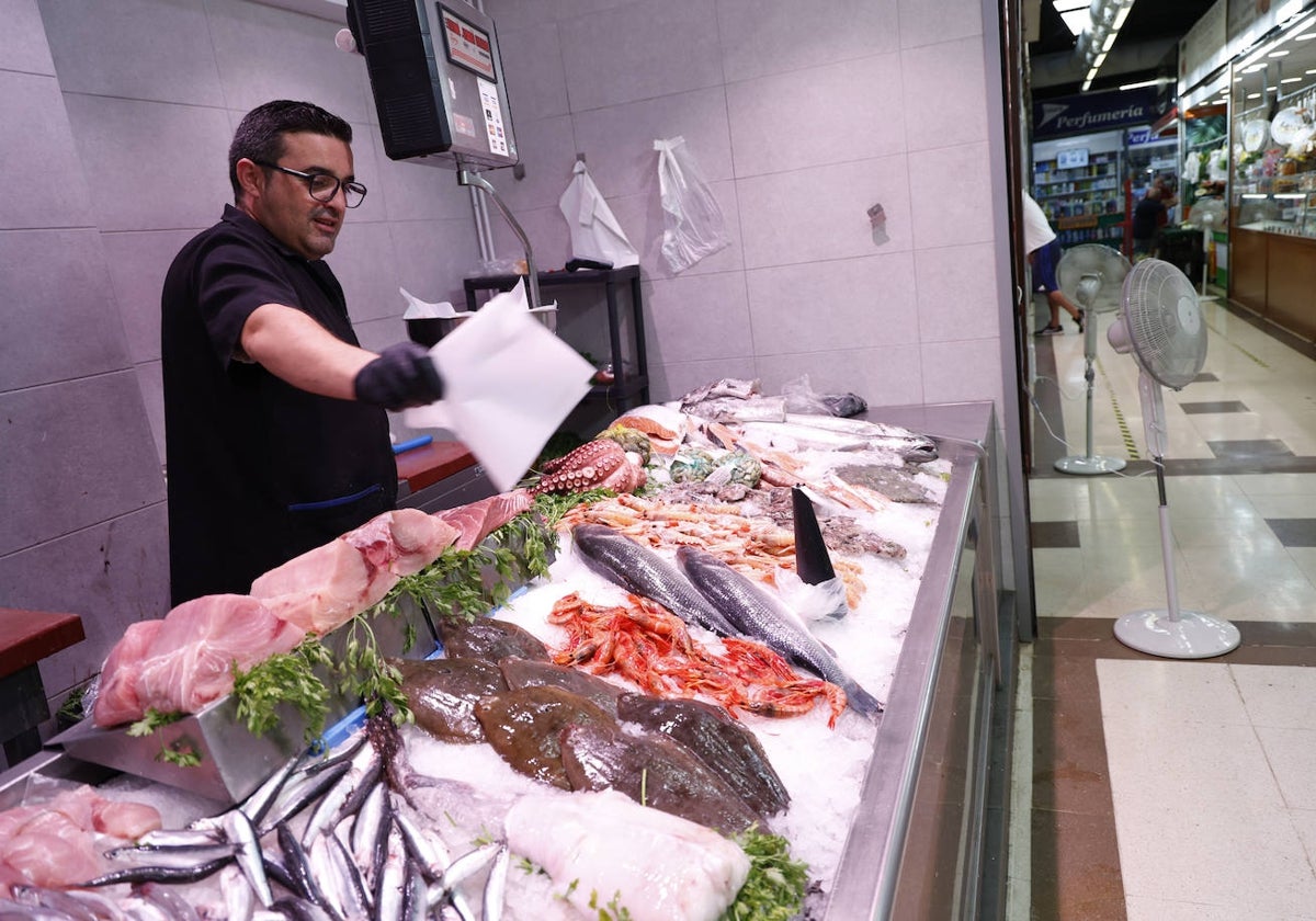 David intenta mantener en buenas condiciones su género en la pescadería que regenta en el mercado de Algirós.