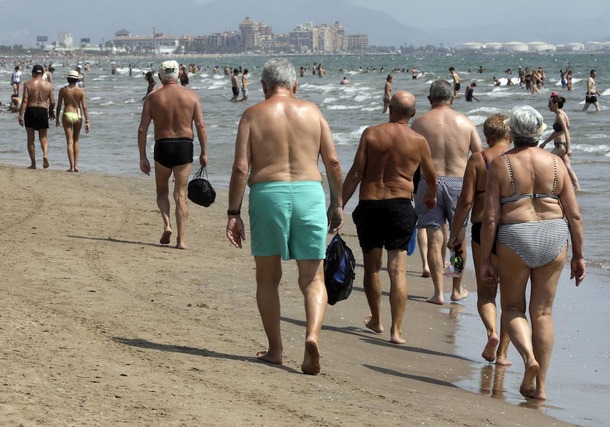 Un grupo de bañistas pasea por una playa de Valencia.