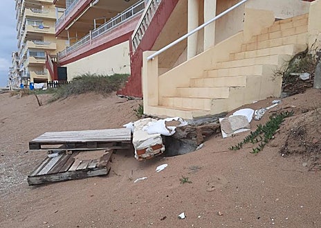 Imagen secundaria 1 - El senador Vicente Martínez y la líder del PP de Tavernes, Eva Palomares, de espaldas, observando el estado de la playa; otros edificios dañados y donde los propietarios han tenido que colocar materiales provisionales para acceder a la arena. 