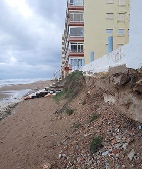Imagen secundaria 2 - El senador Vicente Martínez y la líder del PP de Tavernes, Eva Palomares, de espaldas, observando el estado de la playa; otros edificios dañados y donde los propietarios han tenido que colocar materiales provisionales para acceder a la arena. 