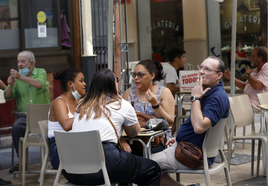 Varios clientes en una terraza hostelera valenciana, uno de ellos fumando.