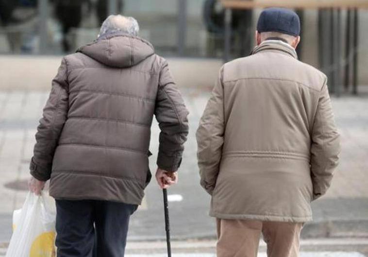 Dos pensionistas pasean por la calle.