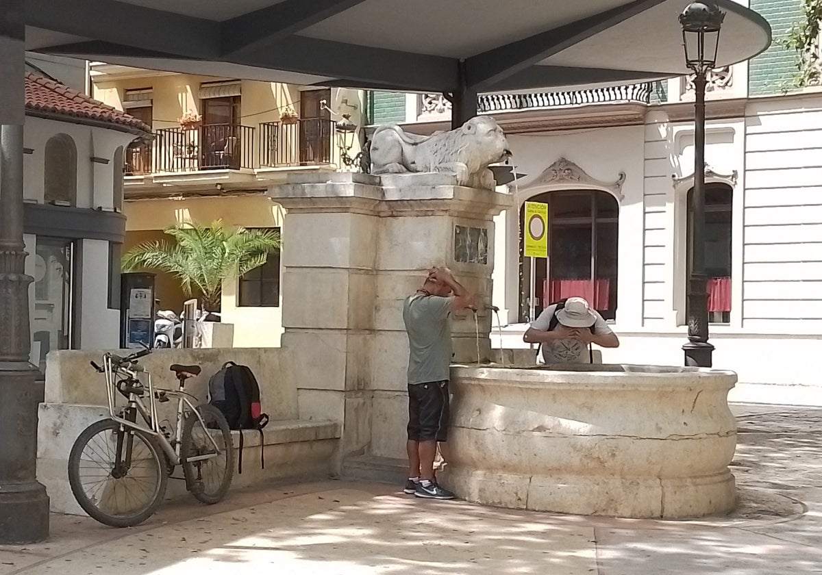 Dos ciudadanos se refrescan en la Fuente del Lleó de Xàtiva.