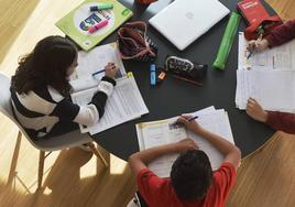 Tres niños hacen sus deberes escolares.