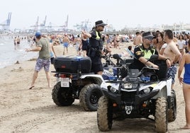 Dos policías locales comunican una incidencia a los bañistas en la playa de Las Arenas.