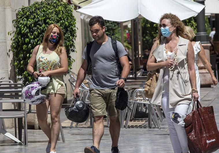 Ciudadanos caminan con mascarillas por una calle de España.