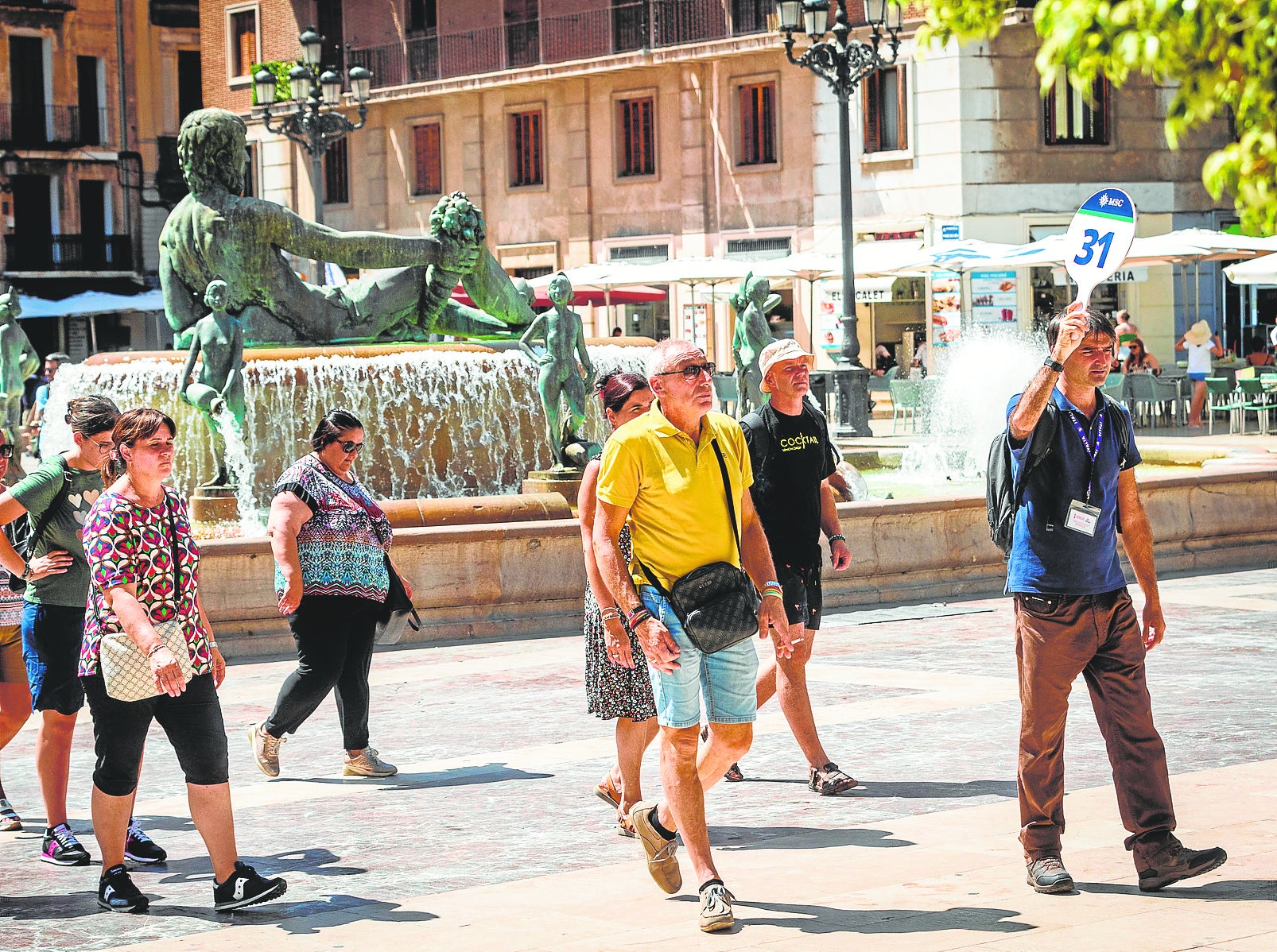 Un grupo de turistas pasea con un guía por la plaza de la Virgen.