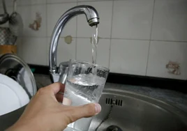 Un vecino llena en su casa un vaso con agua.