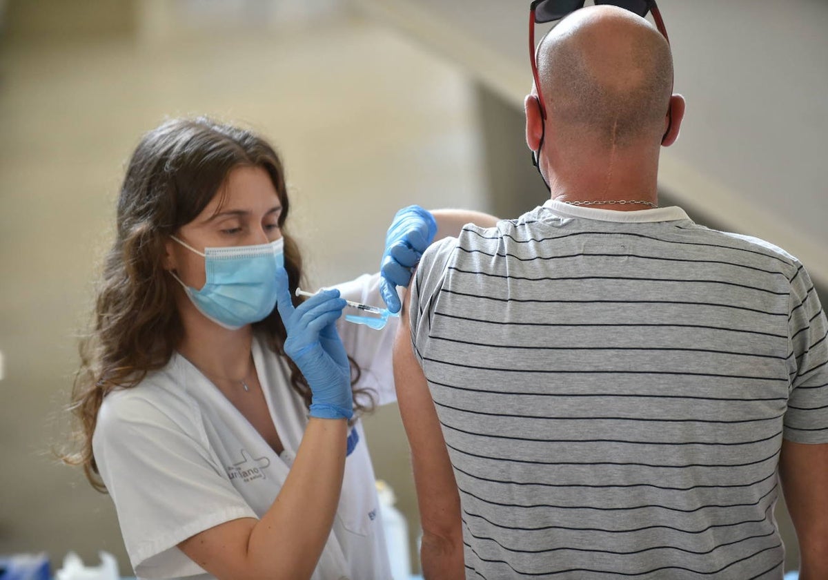 Una sanitaria vacuna a un hombre.