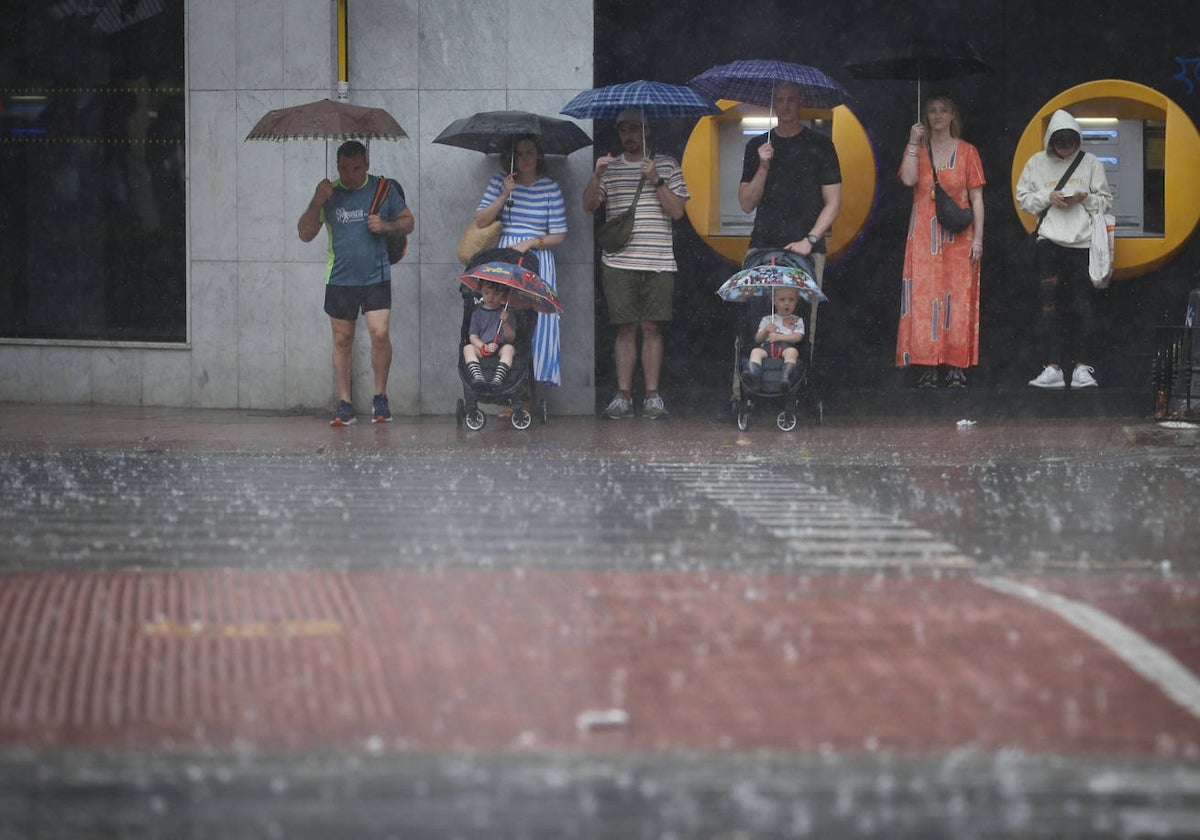 Varias personas se resguardan de la lluvia en Valencia.