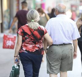 Un pareja de jubilados pasea del brazo