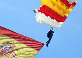 La cabo paracaidista Carmen Gómez Hurtado desciende con una bandera de España en el desfile del Día de las Fuerzas Armadas.