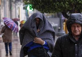 Dos personas se refugian de la lluvia y el frío en Valencia.