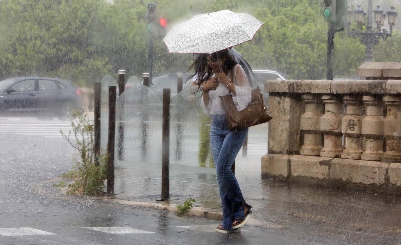 Una mujer se refugia de las fuertes lluvias intensas en la ciudad de Valencia.