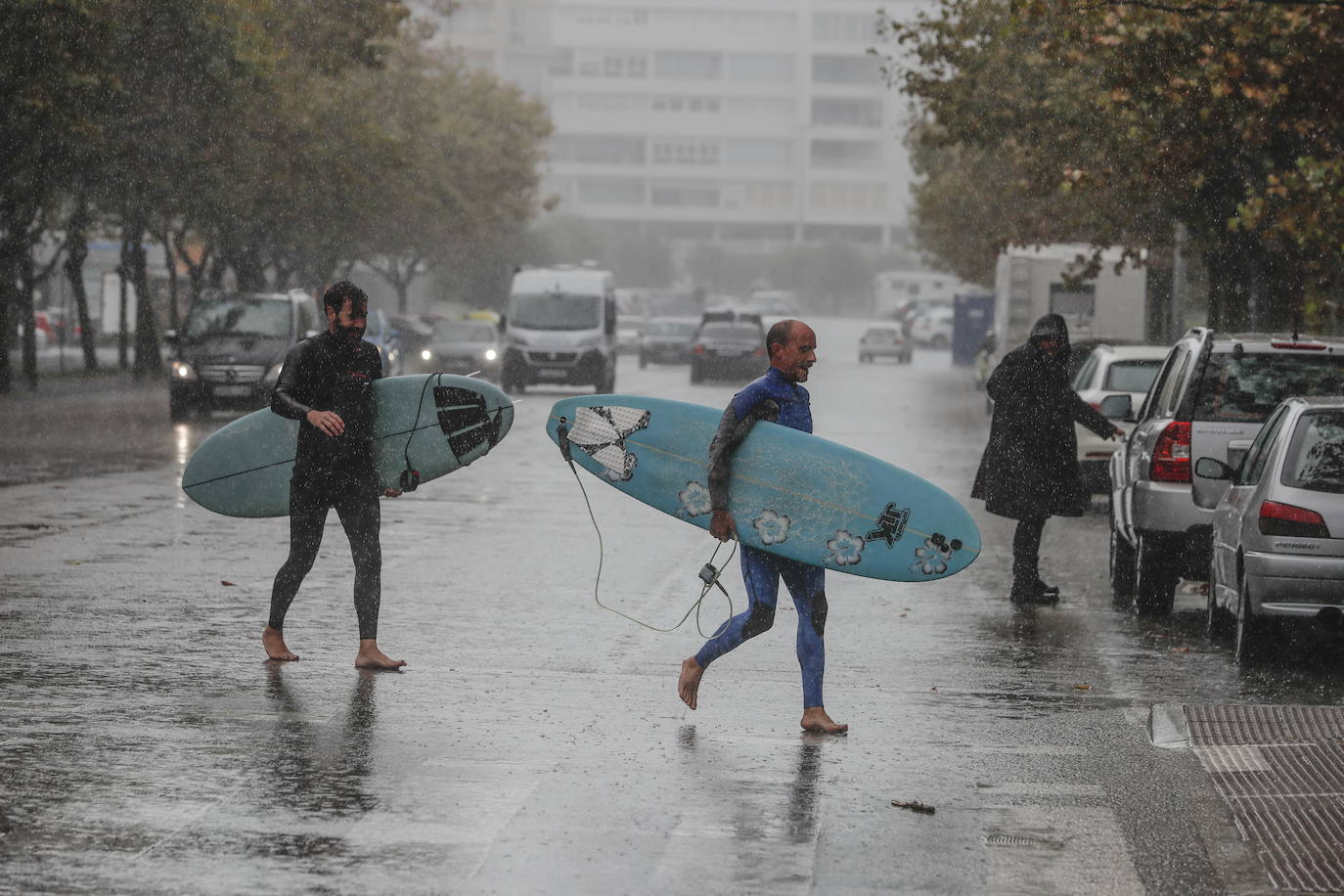 Dos surfistas caminan bajo la lluvia en una imagen de archivo.