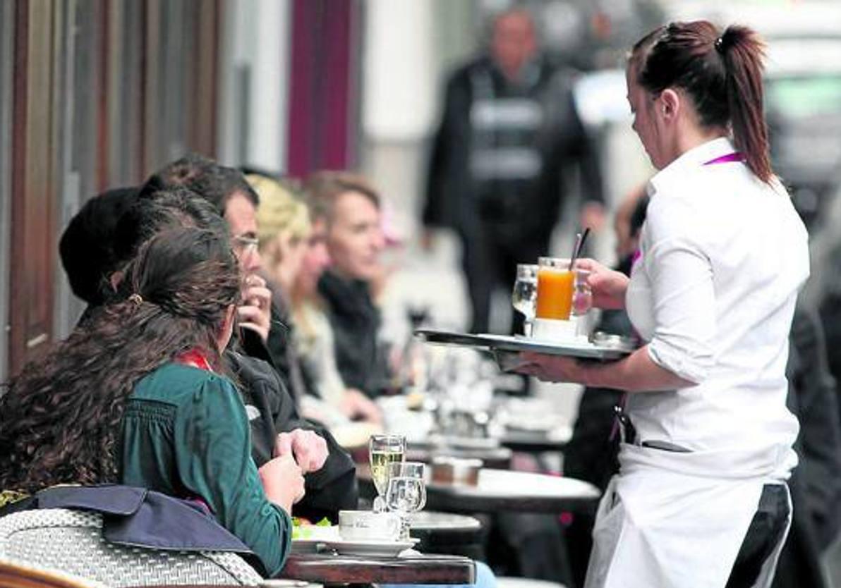 Una camarera durante un servicio en la terraza de un bar.