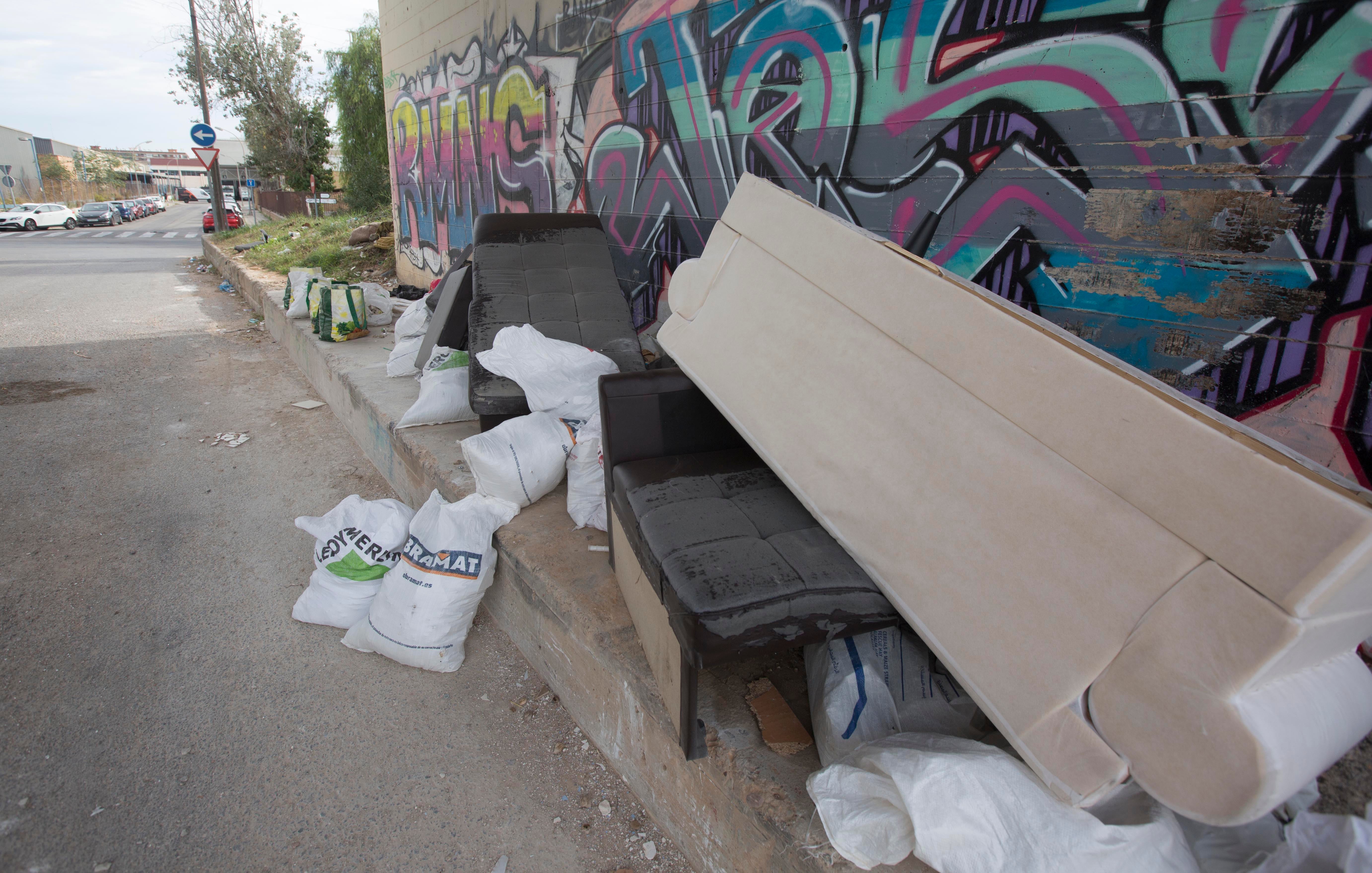 Imagen secundaria 1 - Arriba, la entrada al ecoparque, tomado por los escombros. Muebles y enseres abandonados en un puente junto a la entrada del polígono.