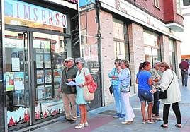 Jubilados hacen cola frente a una agencia de viajes.