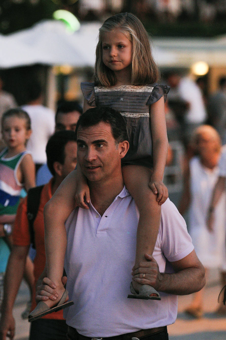 La princesa Leonor, subida a hombros de su padre, el rey Felipe VI, el 6 de agosto de 2012, durante un paseo nocturno por el puerto de la localidad mallorquina de Sóller, tras realizar una excursión familiar, junto a la reina Letizia y la infanta Sofía, en el tren turístico que sale de Palma desde 1912. 