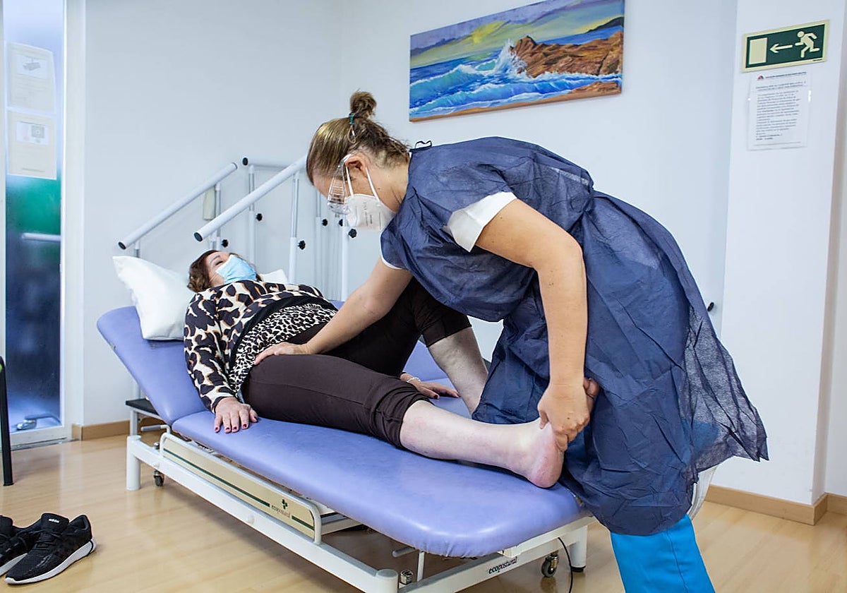 Una sanitaria trabaja con una paciente de esclerosis múltiple.