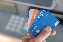 Una persona muestra las diferentes tarjetas que le permiten sacar dinro de un cajero, en una imagen de archivo