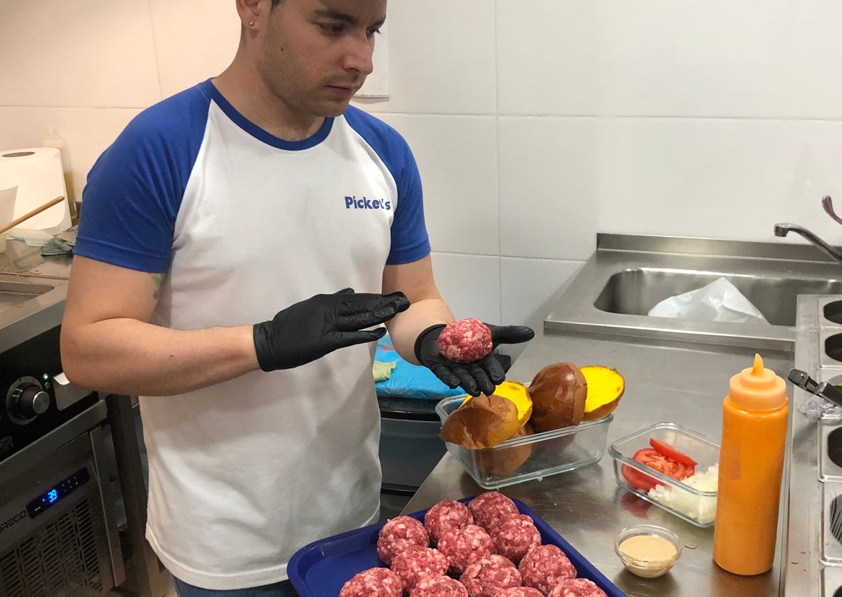 Imagen secundaria 1 - Una hamburguesa y unas patatas, listas para un cliente; un cocinero preparando las hamburguesas con carne recién recibida y unas patatas.