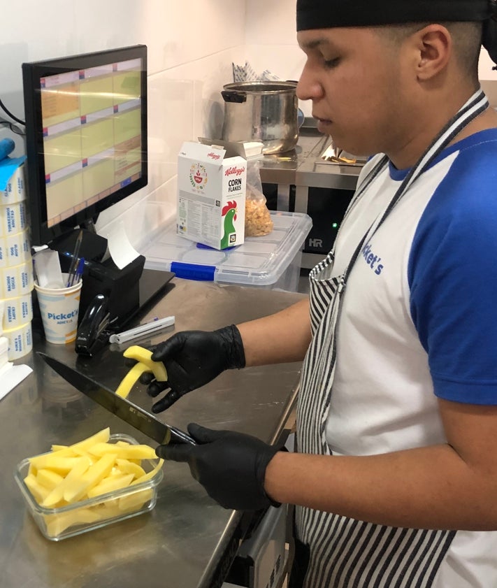 Imagen secundaria 2 - Fede Millet, impulsor del negocio, y un cocinero cortando panceta para los torreznos y preparando patatas frescas para freírlas. 